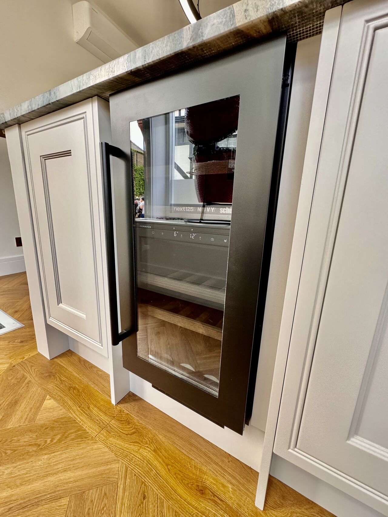 Integrerad helgladad underbänk vinkyl från Dunavox Nordic i köksö med parkettgolv.