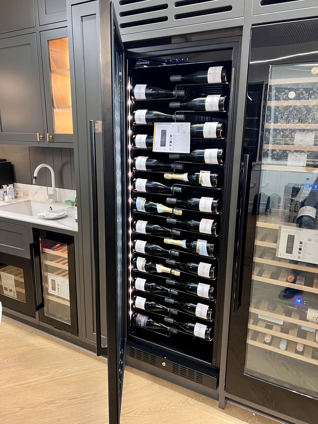 Hög integrerad Dunavox Nordic vinkyl med öppen dörr och vinflaskor i köksmiljö